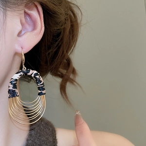 Detailed view of layered golden metal hoops with leopard print fabric texture earring