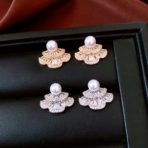 Detailed close-up of vintage fan-shaped earrings with pearls and zircon in gold and silver