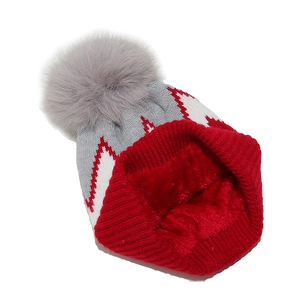 Dettaglio del cappello a maglia rosso e grigio con pompon e calda fodera in pile invernale