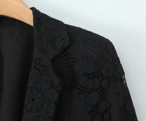 Detailed close-up of intricate black lace blazer neckline and shoulder embroidery texture