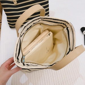 Striped canvas tote bag with brown leather handles and spacious interior for books