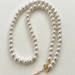 Detailed top view of white pearl necklace with adjustable gold clasp and extension chain
