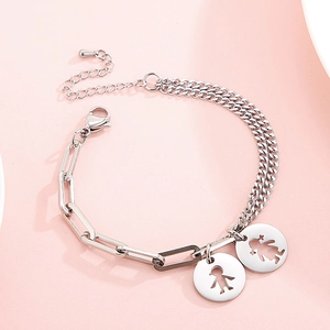 Detail of stainless steel bracelet with cutout boy and girl charms on paperclip chain