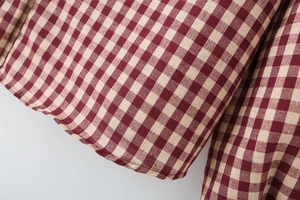 Makroaufnahme von rot-beigem Gingham-Stoff mit feinen Nähten und Webstruktur