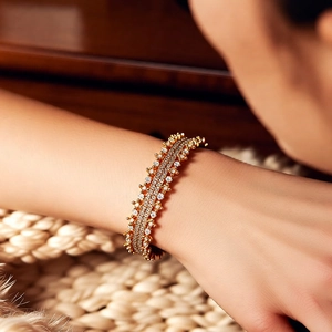 Detailed view of luxury 18k gold plated multi-row crystal bangle on a soft knit background