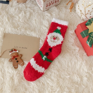 Close-up of red and white fuzzy Christmas socks with a Santa Claus pattern and plush texture