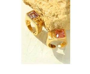 Macro detail of gold plated ring featuring a rectangular purple gemstone and GoodLuck engraving