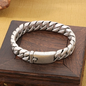 Close-up of vintage silver Cuban chain bracelet with a secure clasp on a wood box
