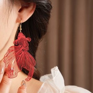 Vue détaillée d'une boucle d'oreille carpe koi rouge portée par un mannequin de profil