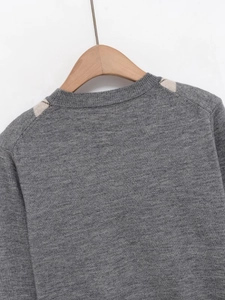 Detail showing the ribbed round neck and argyle pattern on a grey knit cardigan