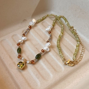 Detail view of 18k gold plated necklace with green square gem and baroque pearls