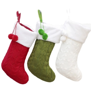 Three knitted Christmas stockings in red, green and white with plush cuffs and pom poms