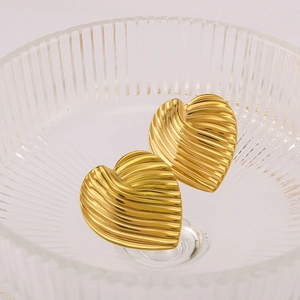 Minimalist gold stainless steel heart earrings with ribbed texture in a glass bowl