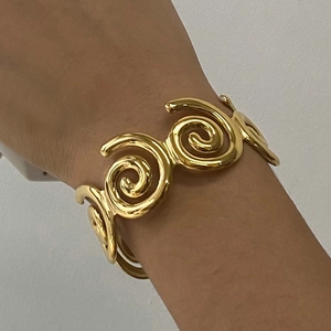 Close-up of a gold-plated spiral cuff bracelet with hollow design on a female wrist