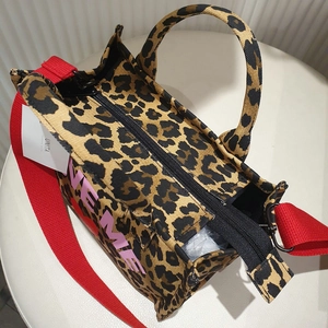 Detail view of leopard print tote bag with red strap and Love Me text pattern