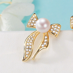 Golden bow stud earrings with white freshwater pearl and sparkling pavé crystals