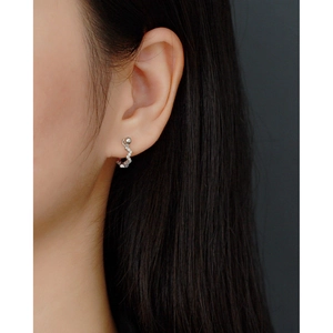 Close-up of wavy 925 sterling silver stud earring with tiny zircons worn on ear