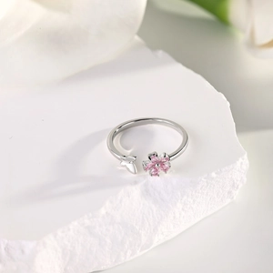 Detail of silver leaf ring with pink zircon flower and butterfly on white stone