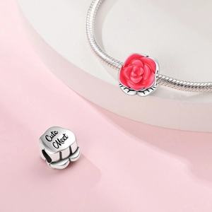 Detail of red rose charm with Cute Meet engraving on a silver snake chain bracelet