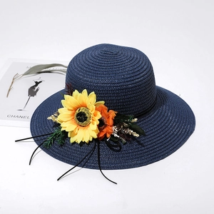 Detail of dark blue woven straw sun hat featuring sunflower and floral accents