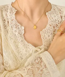 Irregular oval pendant necklace and chunky chain ring worn by a model in lace attire