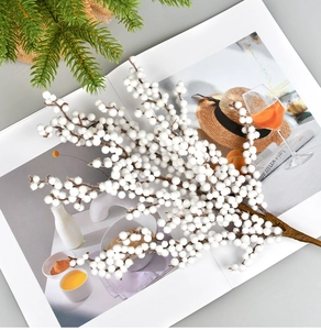 Close-up of white artificial berry stem on an open book with green pine needles