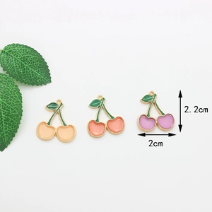 Détail de breloques cerise de 2,2x2cm en émail rose et violet avec base dorée