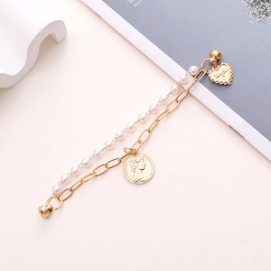 Close-up of double-layer bracelet with pearl chain, gold coin and heart charms