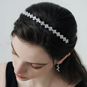 Detailed view of silver leaf-shaped headband with sparkling clear zircon on model