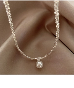 Macro shot of silver pearl necklace with zirconia on elegant champagne satin fabric