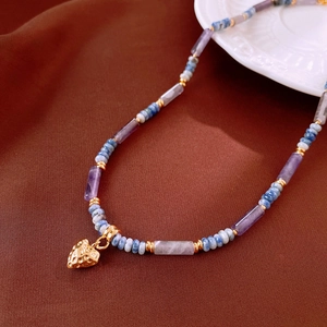 Detail of beaded necklace featuring blue and purple stones with a gold heart pendant