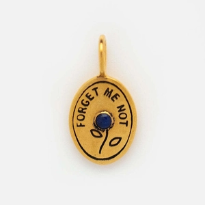 Detail of oval gold pendant with blue gemstone flower and Forget Me Not engraving
