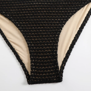 Close-up of black crochet bikini bottom showing intricate knit texture and beige lining