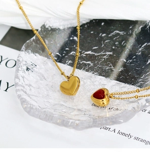 Detail of elegant gold heart pendant necklace with red agate inlay on a glass plate