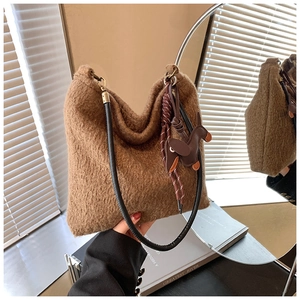 Brown wool shoulder bag with black leather strap and cute doll pendant on books