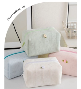 Dettaglio di pochette trucco con fiori in maglia a nido d'ape, colori menta, rosa e beige