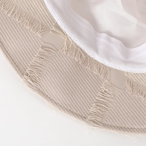 Close-up of woven straw sun hat detailing beige fabric and stylish fringe edges