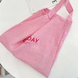 Close-up of pink canvas tote bag with red letter print and soft cotton texture