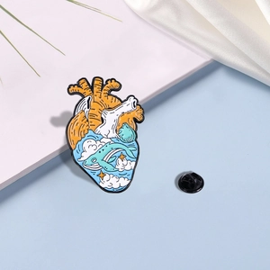 Macro shot of an enamel heart brooch with whale and star patterns on blue background