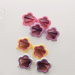 Close-up of four colorful flower-shaped sunglasses for girls in a stylish flat lay
