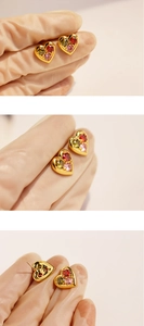 Macro shot of gold heart-shaped earrings featuring colorful zircon stones in close-up view