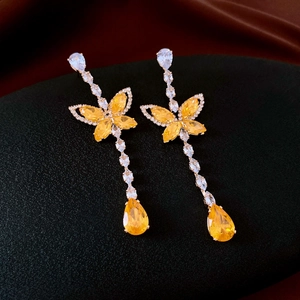 Détail de boucles d'oreilles papillon en zircon jaune avec longs pompons sur présentoir