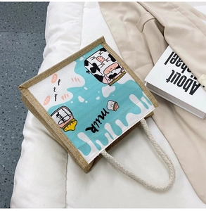 Detail of canvas tote bag featuring a cute cartoon cow print and rustic rope handles