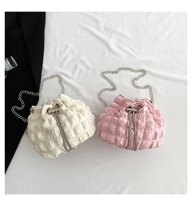 Detail view of stylish drawstring bucket bags with chain straps in beige and pink