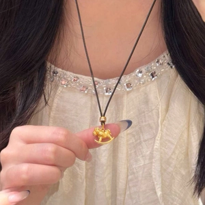 Detail of 24k gold plated rocking horse pendant with zircon on a black cord necklace