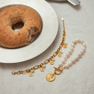 Detail of baroque pearl bracelet with gold queen coin charms and OT buckle design