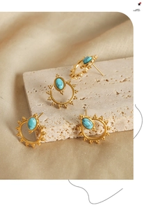 Detail of vintage gold sunburst earrings with turquoise stone on champagne silk fabric