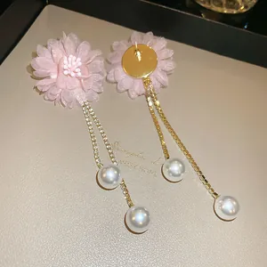 Detail view of pink tulle flower earrings with gold tassel chains and pearls