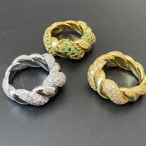Detailed top view of twisted design rings with green and white cubic zirconia accents