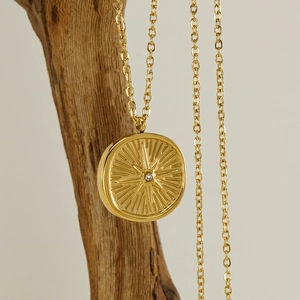 Golden North Star pendant necklace with small crystal diamond on a rustic wooden stand